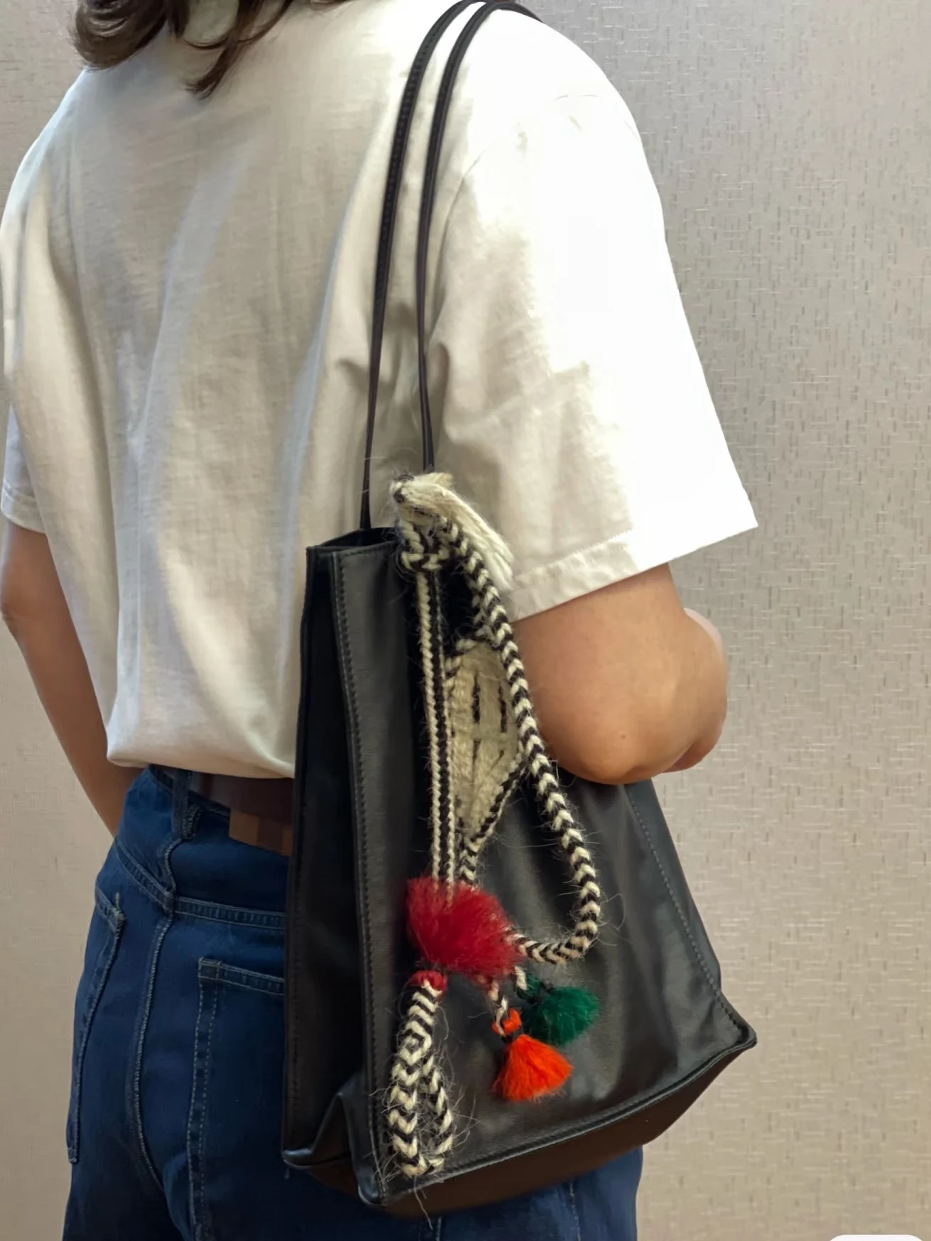 Classic wurdoo sling with red, green and orange tassels on a woman's leather tote bag